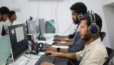 Two team members in headsets working at their desks on the studio floor.